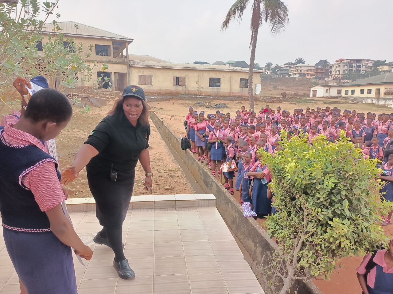 Female CHAPOL officer engaging students in pink uniforms